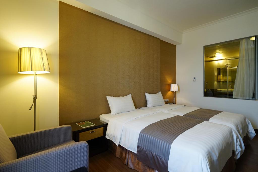een hotelkamer met een groot bed en een stoel bij Hai Yue Hotel in Magong