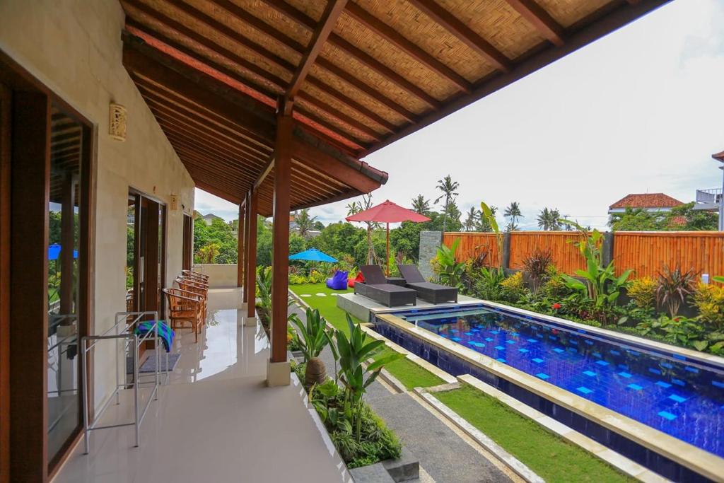 un patio al aire libre con piscina y una casa en Rahma Guesthouse, en Canggu