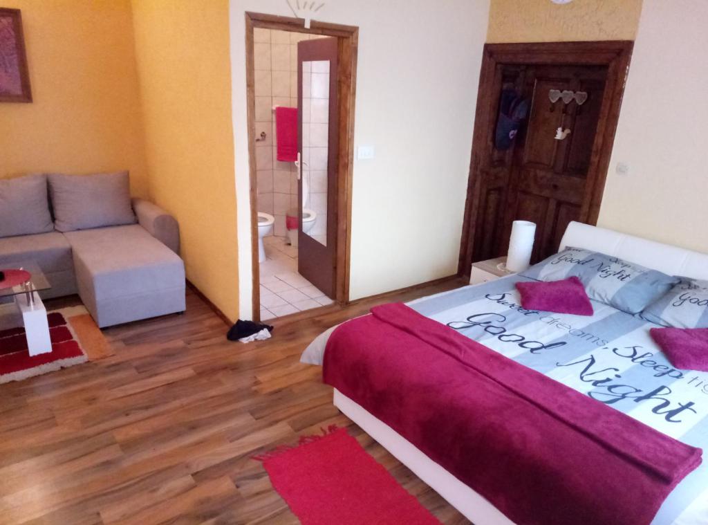 a bedroom with a bed and a living room with a couch at Guesthouse Zeko in Aljmaš