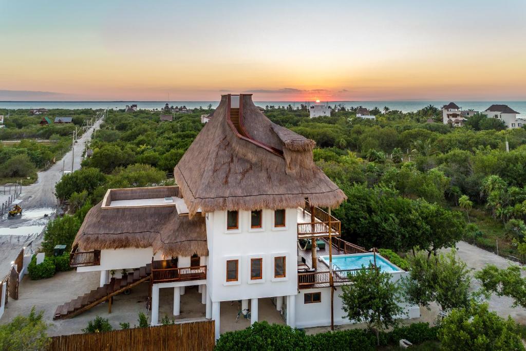 una casa con techo de paja y una puesta de sol en el fondo en Casa HM Villa del Mar, en Isla Holbox