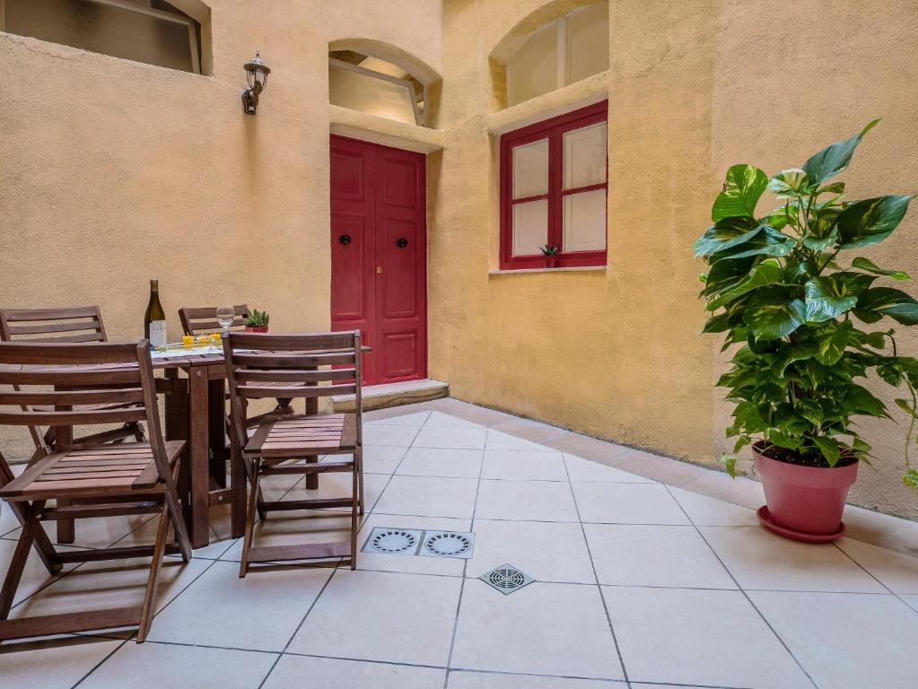 patio con mesa, sillas y puerta roja en Valletta Main Street Apartment en La Valeta