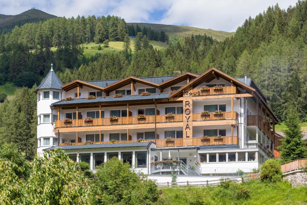 a large hotel in the mountains with trees at Hotel Royal und Ferienhaus Annabel in Sesto