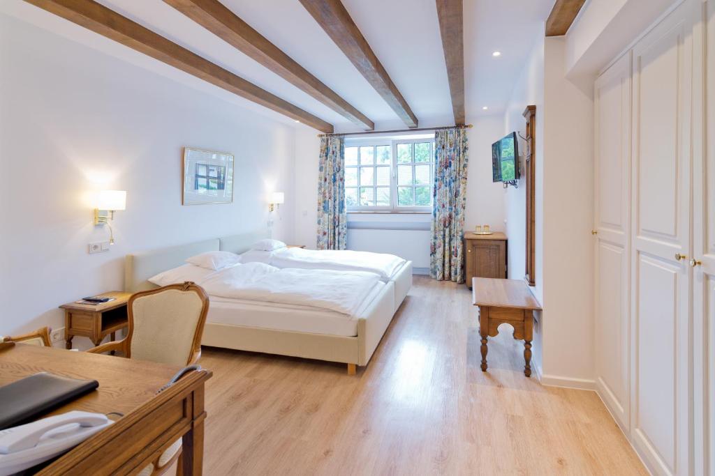 Schlafzimmer mit einem weißen Bett, einem Schreibtisch und einem Fenster in der Unterkunft Romantik Waldhotel Mangold in Bergisch Gladbach
