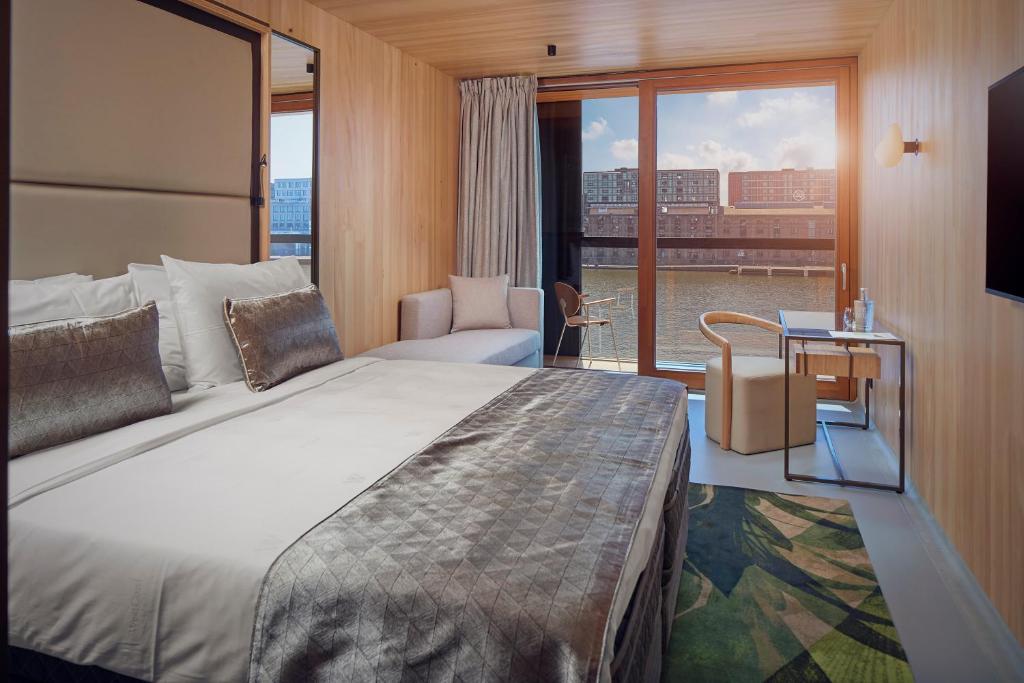 アムステルダムにあるホテル ジャカルタ アムステルダムの大きなベッドと窓が備わるホテルルームです。