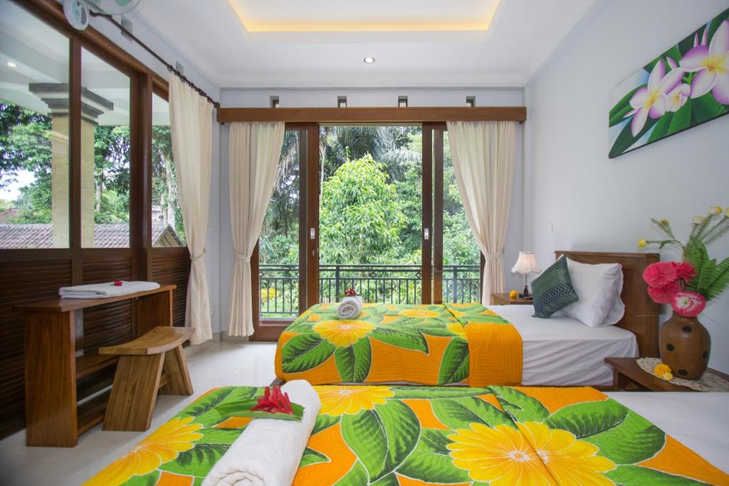 een slaapkamer met 2 bedden en een balkon bij Telaga Homestay Ubud in Ubud