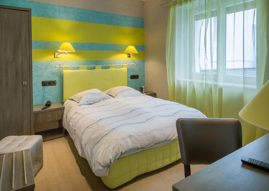a bedroom with a bed and a desk and a window at Hostellerie De La Mer in Crozon