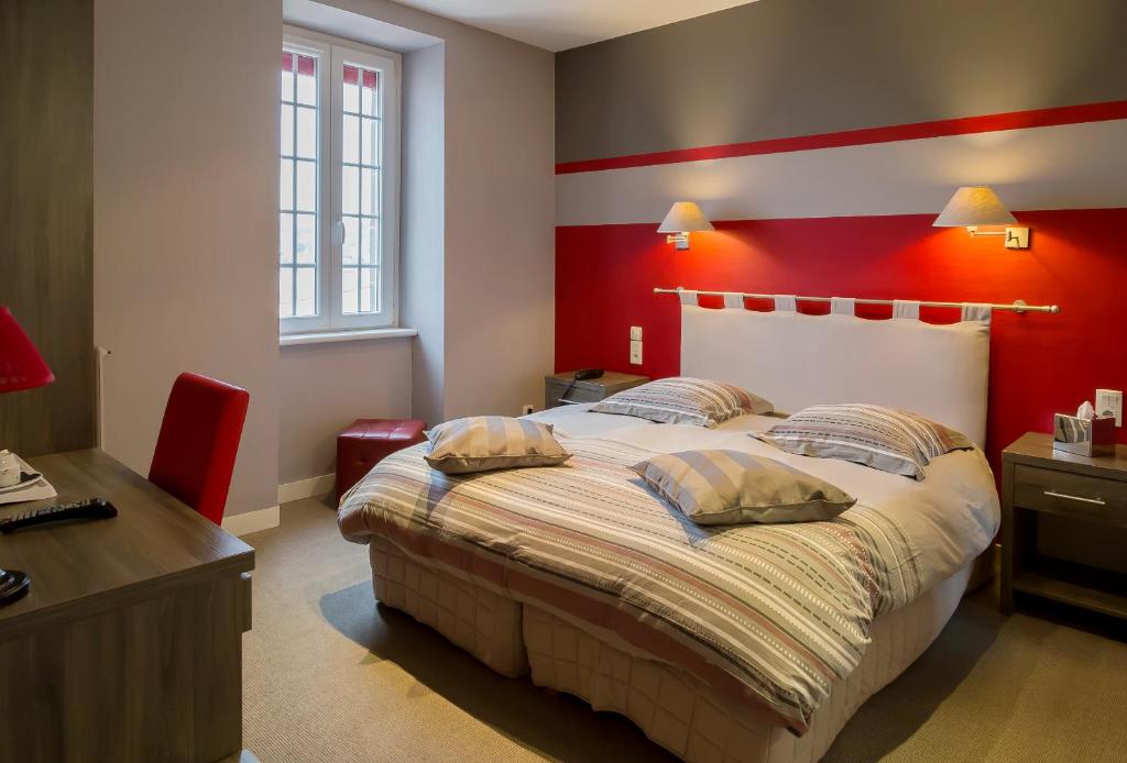 a bedroom with a large bed with a red wall at Hostellerie De La Mer in Crozon