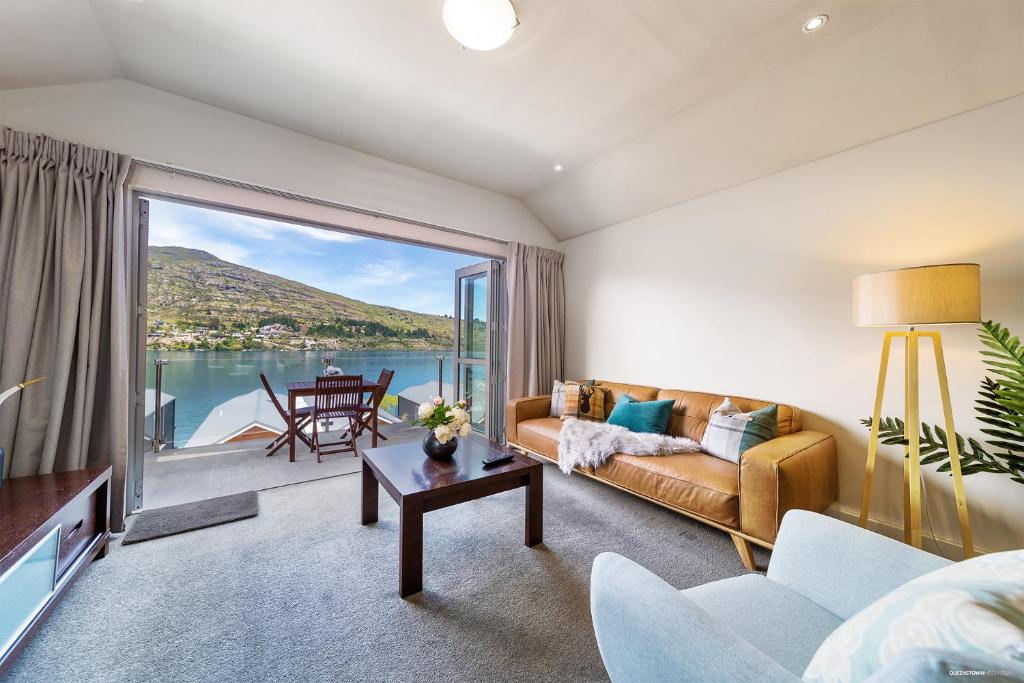 a living room with a couch and a large window at Alpine Village - 2 Bedroom Executive Apartment in Queenstown