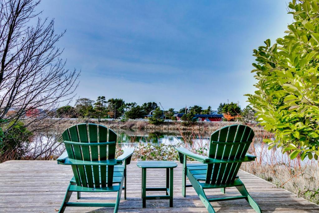 two green chairs sitting on a dock near a lake at The River Belle in Seaside
