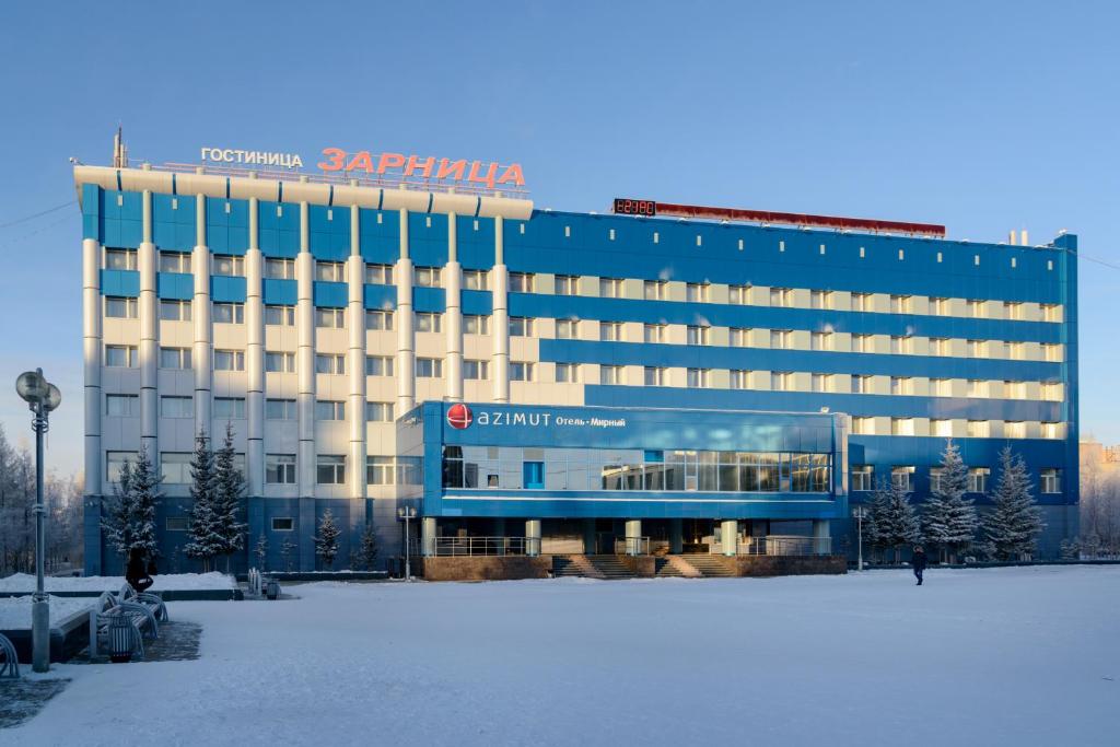 a hotel with a blue and white building in the snow at AZIMUT Hotel Mirny in Mirnyy