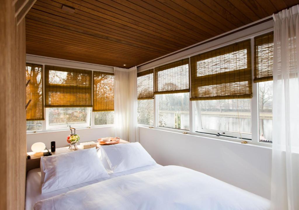1 dormitorio con ventanas y 1 cama con sábanas blancas en SWEETS - Buiksloterdraaibrug en Ámsterdam