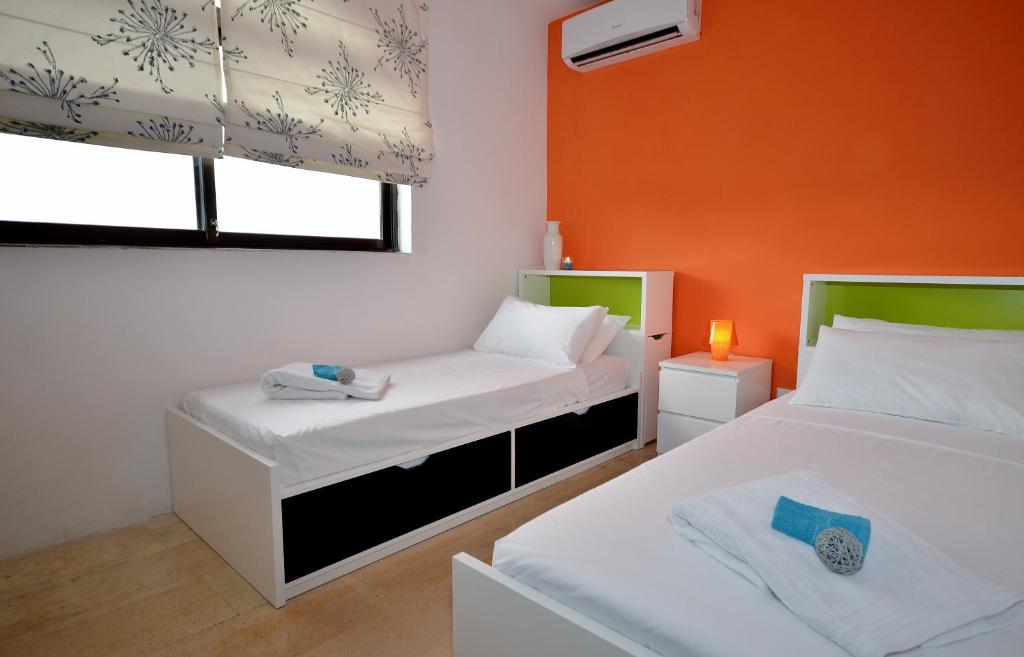 2 łóżka w pokoju z pomarańczową ścianą w obiekcie City Living Suite Tk 3 Rm 3 w mieście St. Julian’s