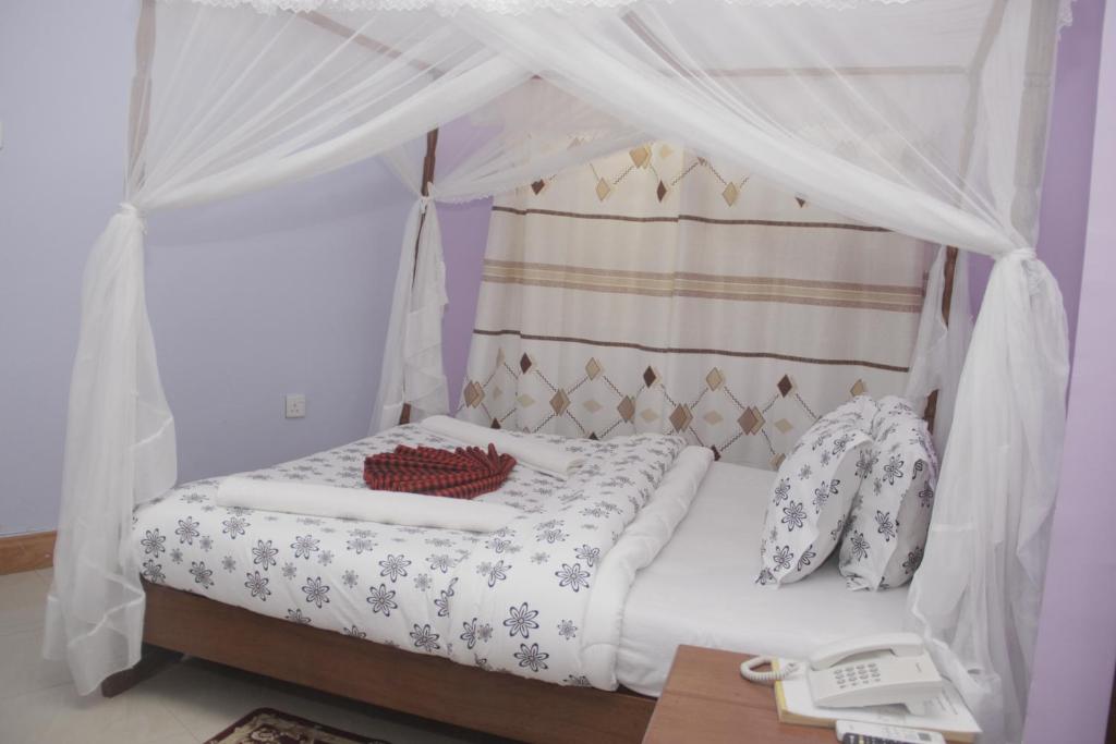 a bed with a canopy in a room at Arusha Giraffe Lodge in Arusha