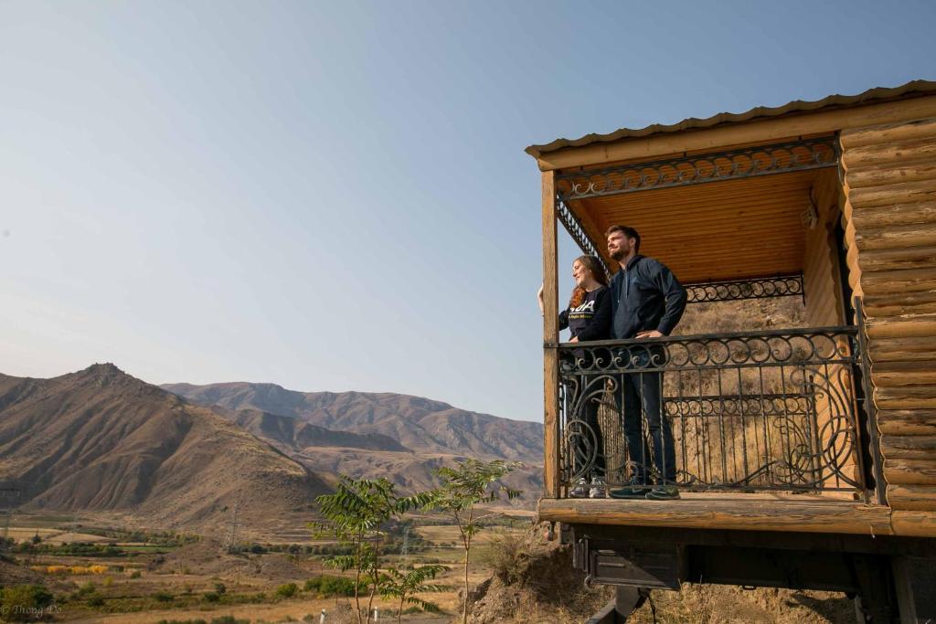 two people standing on a balcony of a house at Arpa Valley Cabin in Yeghegnadzor