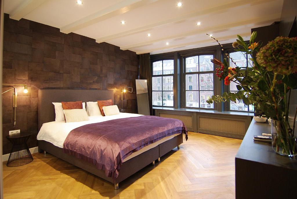 a bedroom with a bed and a large window at The Canal Bridge Suites in Amsterdam