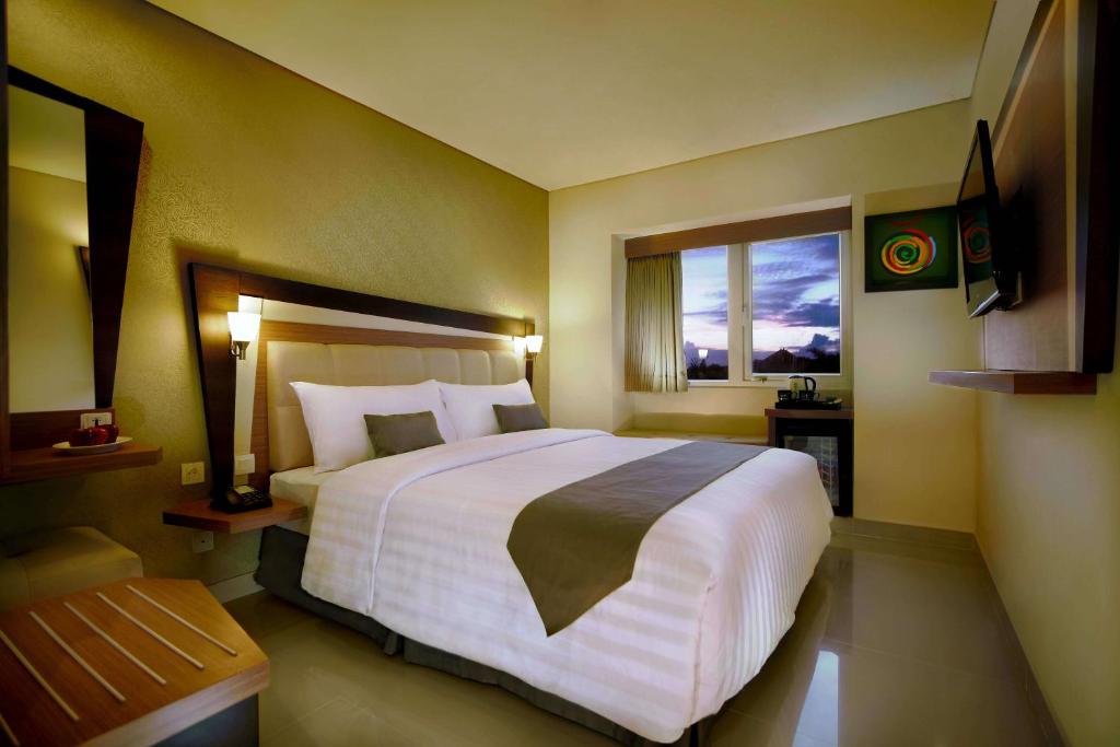 a hotel room with a large bed and a window at Hotel Neo - Kuta, Jelantik in Legian