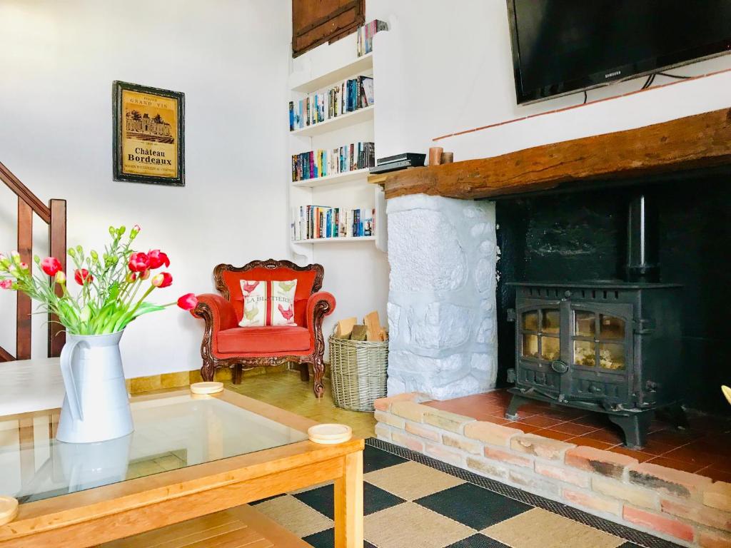 a living room with a fireplace and a red chair at La Blatière French Cottages in La Chapelle-Saint-Étienne