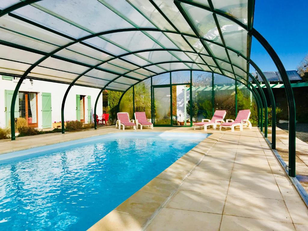 a swimming pool with pink chairs and a glass house at La Blatière French Cottages in La Chapelle-Saint-Étienne