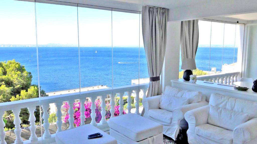 sala de estar con sillas blancas y balcón con vistas al océano en Breathtaking Costabrava seaview apartment 5m beach - Casa ArteVida en Roses