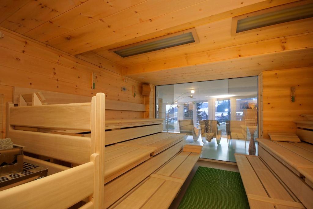 un sauna avec des murs en bois et un sol vert dans l'établissement Panorama Hotel Kaserer, à Fischen im Allgäu