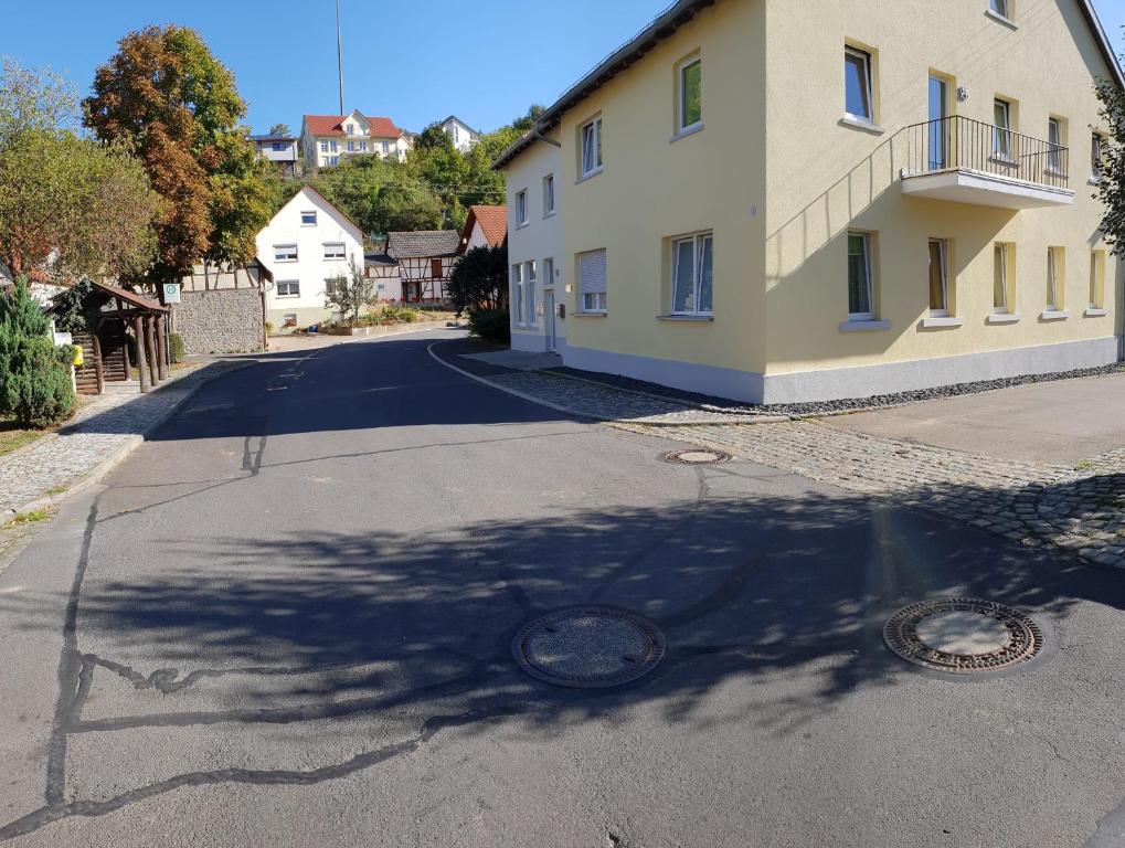 eine leere Straße mit einem Gebäude und einem Baum darüber in der Unterkunft Monteurzimmer Ferienwohnungen Fritsche-Tauberbischofsheim in Dittwar