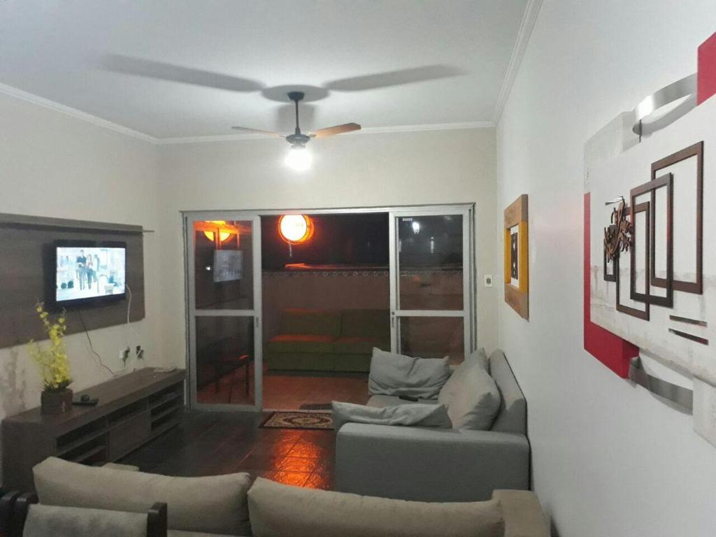 a living room with a couch and a ceiling fan at Apt. Enseada Guarujá in Guarujá