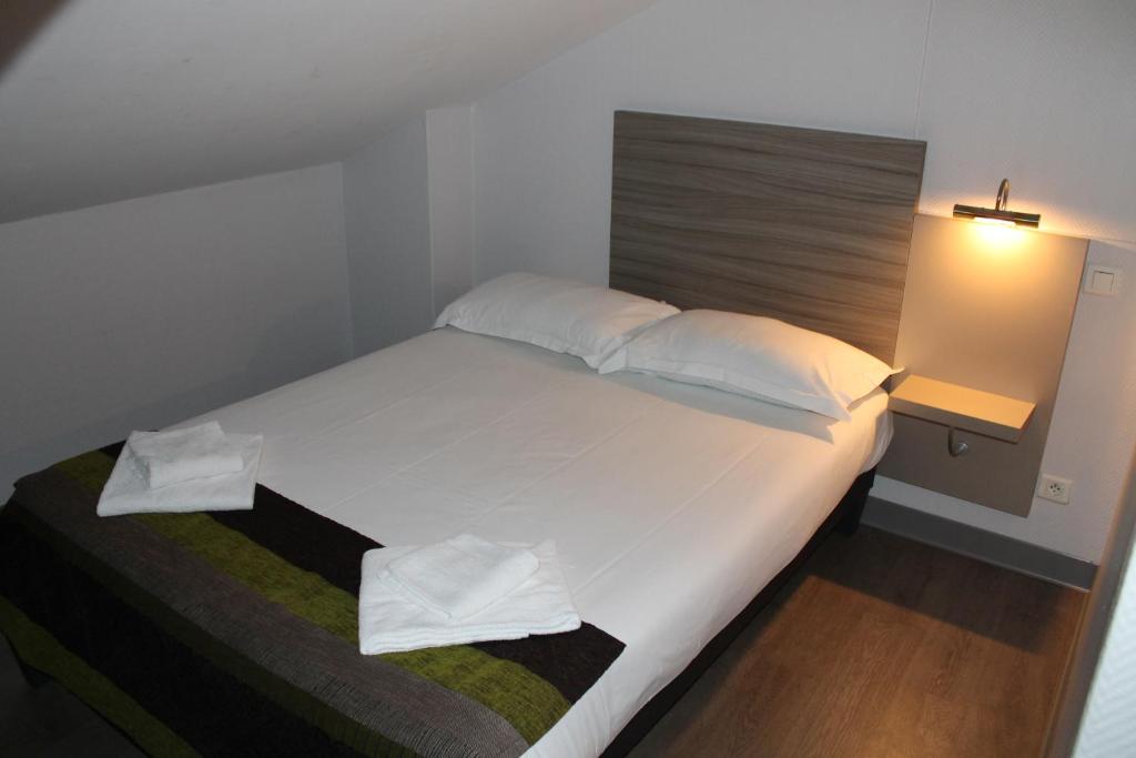a bedroom with a large bed with white sheets and pillows at Hôtel du Centre in Soustons