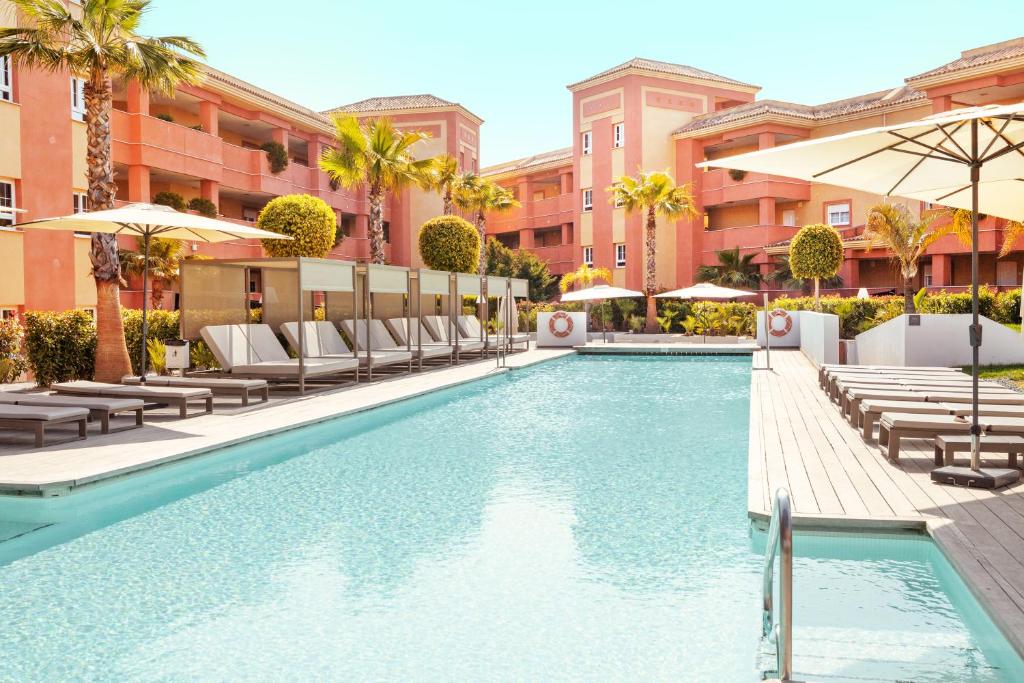 a swimming pool with chairs and umbrellas at a hotel at Ama Islantilla Resort in Islantilla
