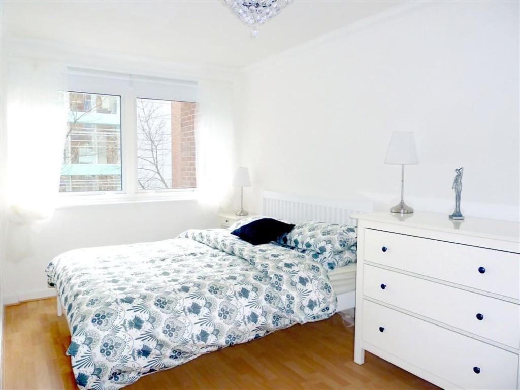 ein weißes Schlafzimmer mit einem Bett und einer Kommode in der Unterkunft Elegant Fitzrovia 2-bed w Wifi: Close to Oxford Street W1 in London
