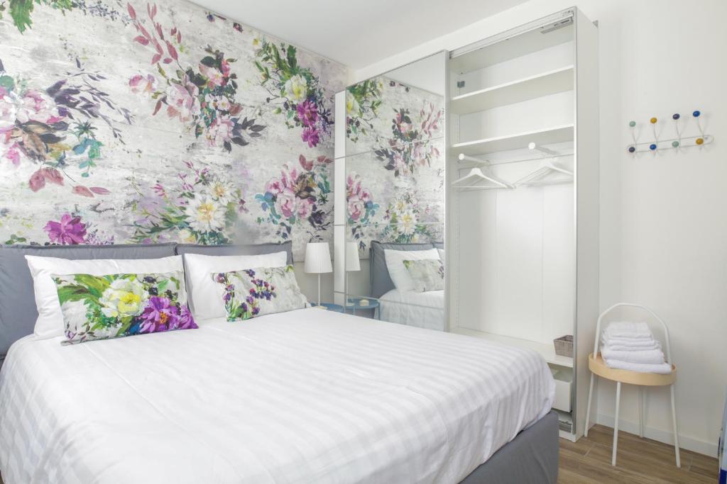 1 dormitorio con 1 cama blanca con flores en la pared en Charming and cosy apartment, en Bolonia