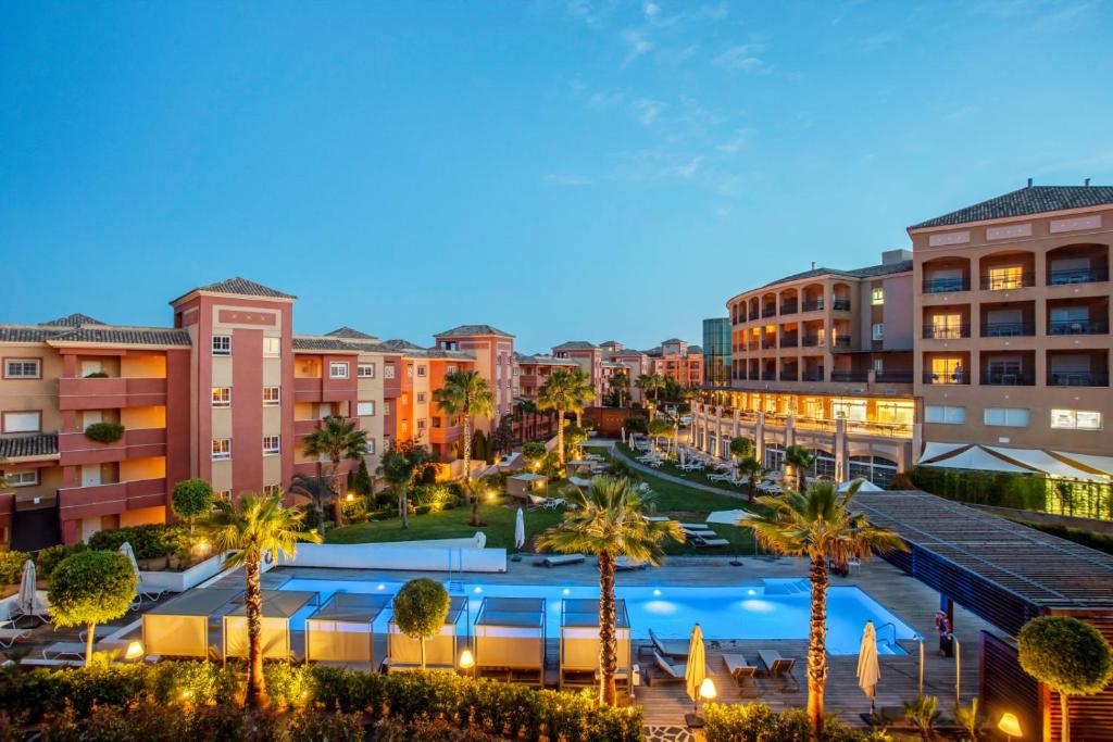 a city at night with palm trees and buildings at Ama Islantilla Resort in Islantilla