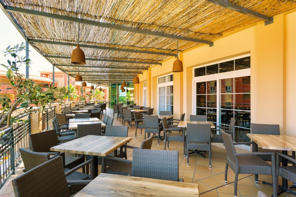 a restaurant with tables and chairs on a patio at Ama Islantilla Resort in Islantilla