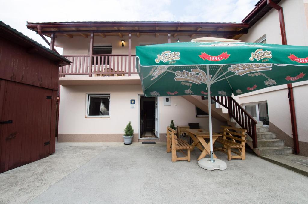 eine Terrasse mit einem Tisch und einem grünen Sonnenschirm in der Unterkunft Rooms Sejo in Kolašin