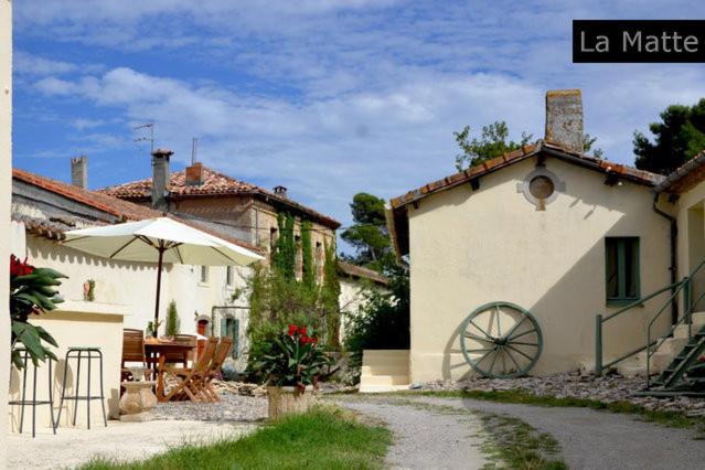 een huis met een paraplu, een tafel en een patio bij Domaine de la Matte in Conques-sur-Orbiel