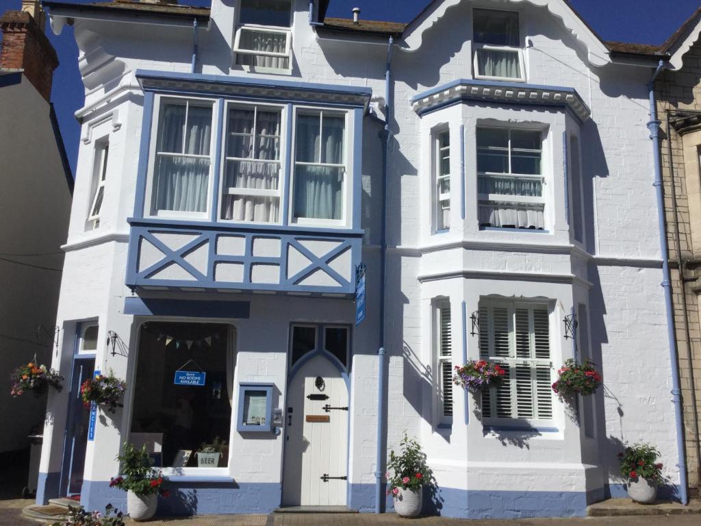 ein blau-weißes Haus mit Blumen davor in der Unterkunft Colebrooke House in Beer