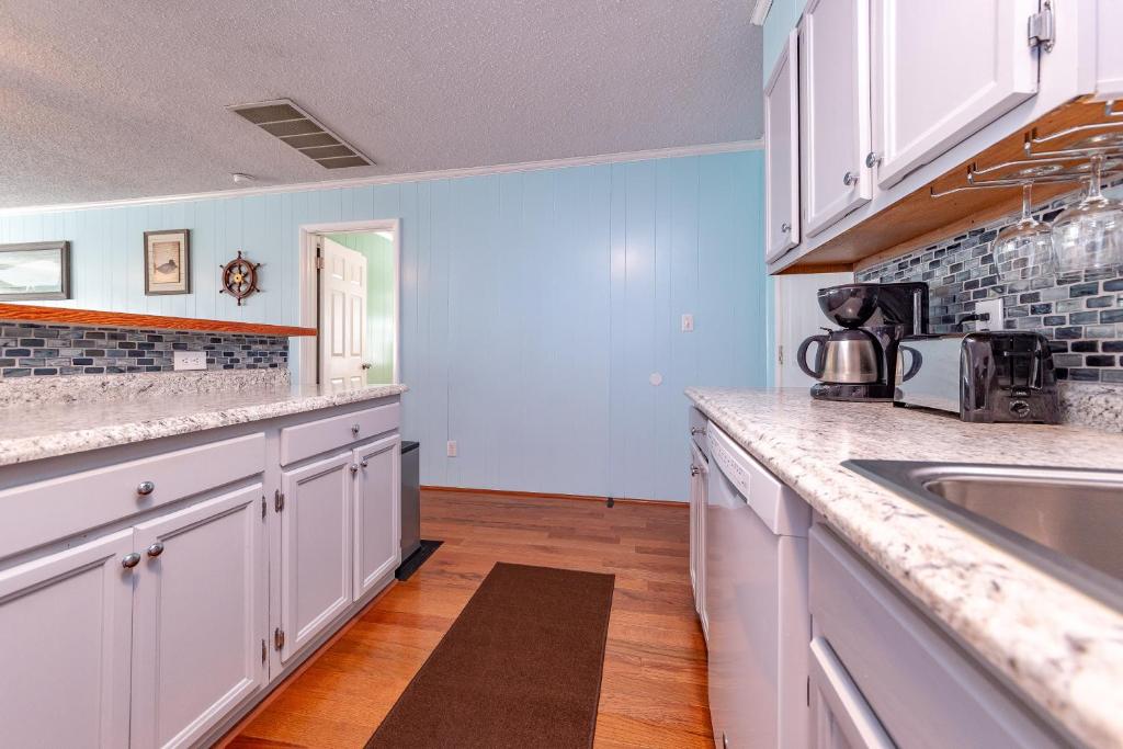 a kitchen with white cabinets and a sink at Landing Pad in Kill Devil Hills