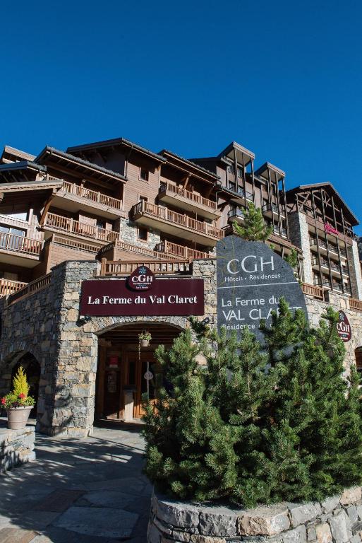 un bâtiment avec un panneau et un arbre devant lui dans l'établissement CGH Résidences & Spas La Ferme Du Val Claret, à Tignes