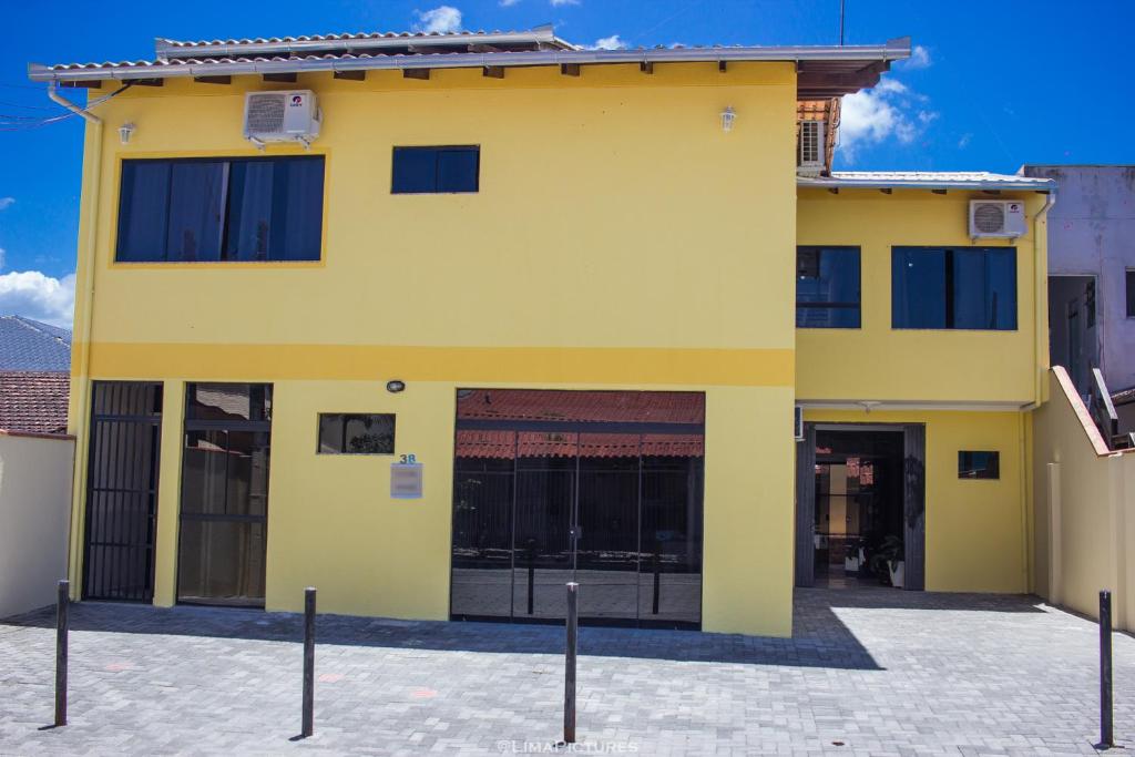 un edificio amarillo con puertas y ventanas negras en Pousada Sol de Maria en Penha