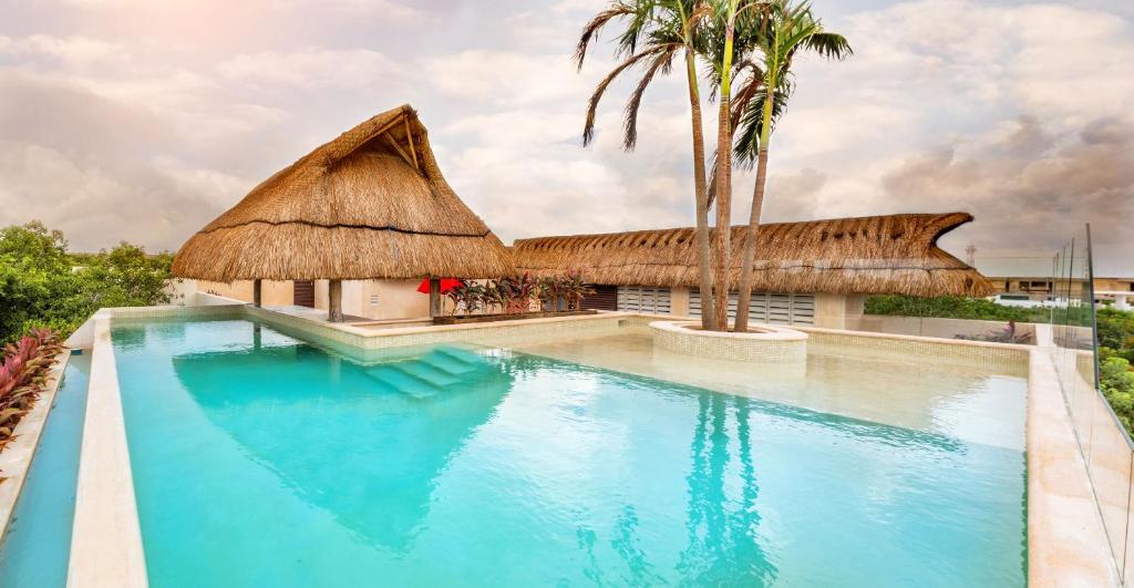 a resort swimming pool with a thatched roof at Albra Tulum in Tulum