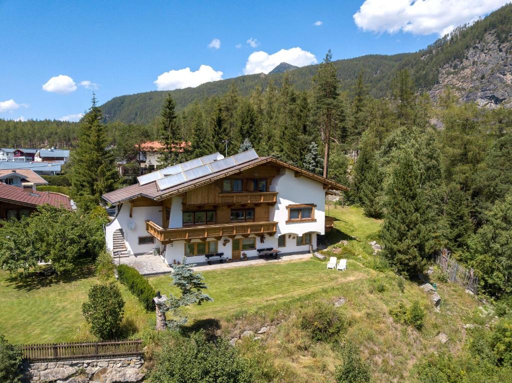 una casa en una colina con montañas en el fondo en Haus Raimund, en Längenfeld