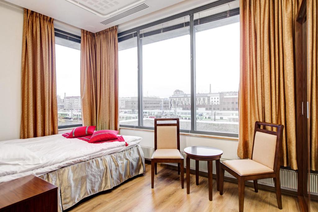 a bedroom with a bed and two chairs and windows at Hotel Citi Inn in Tampere