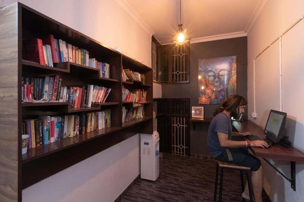 a woman sitting at a desk with a computer in a library at Hoztel Jaipur in Jaipur