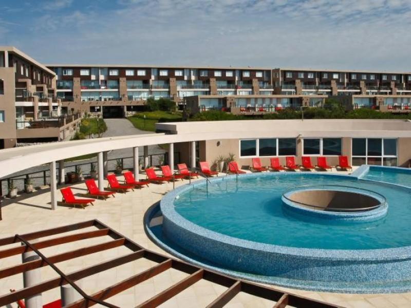 uma grande piscina com cadeiras vermelhas e um edifício em Linda Bay Beach & Resort em Mar de las Pampas