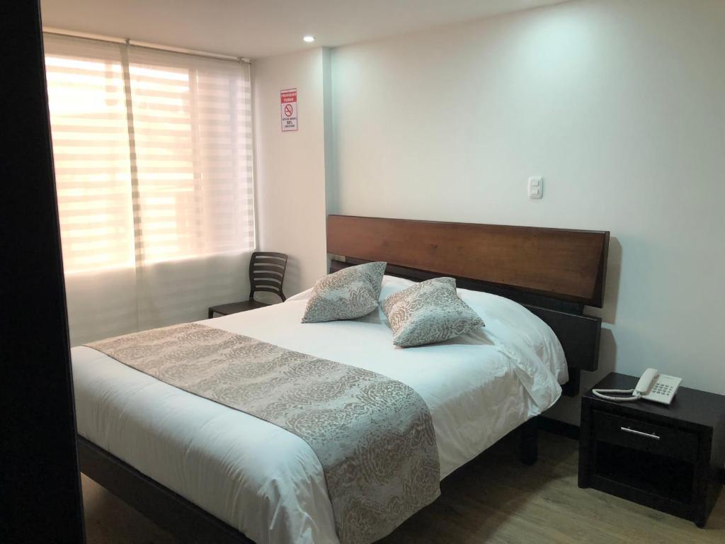 een slaapkamer met een bed met 2 kussens erop bij Hotel Florida ApartaSuites. in Ipiales