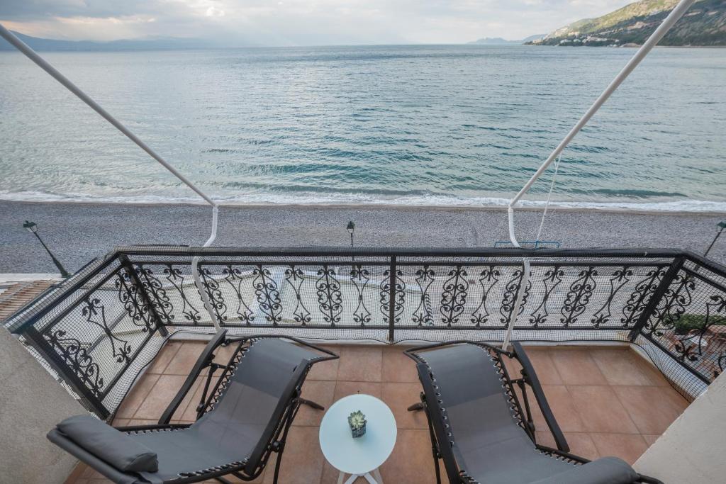 een balkon op een schip met stoelen en een tafel bij Amazing condo by the beach in Loutraki