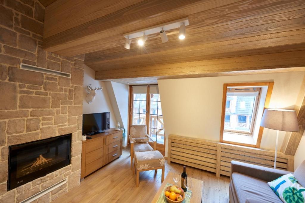 a living room with a stone fireplace and a couch at LUX privatni apartman 411 u sklopu HOTEL VUČKO JAHORINA in Jahorina