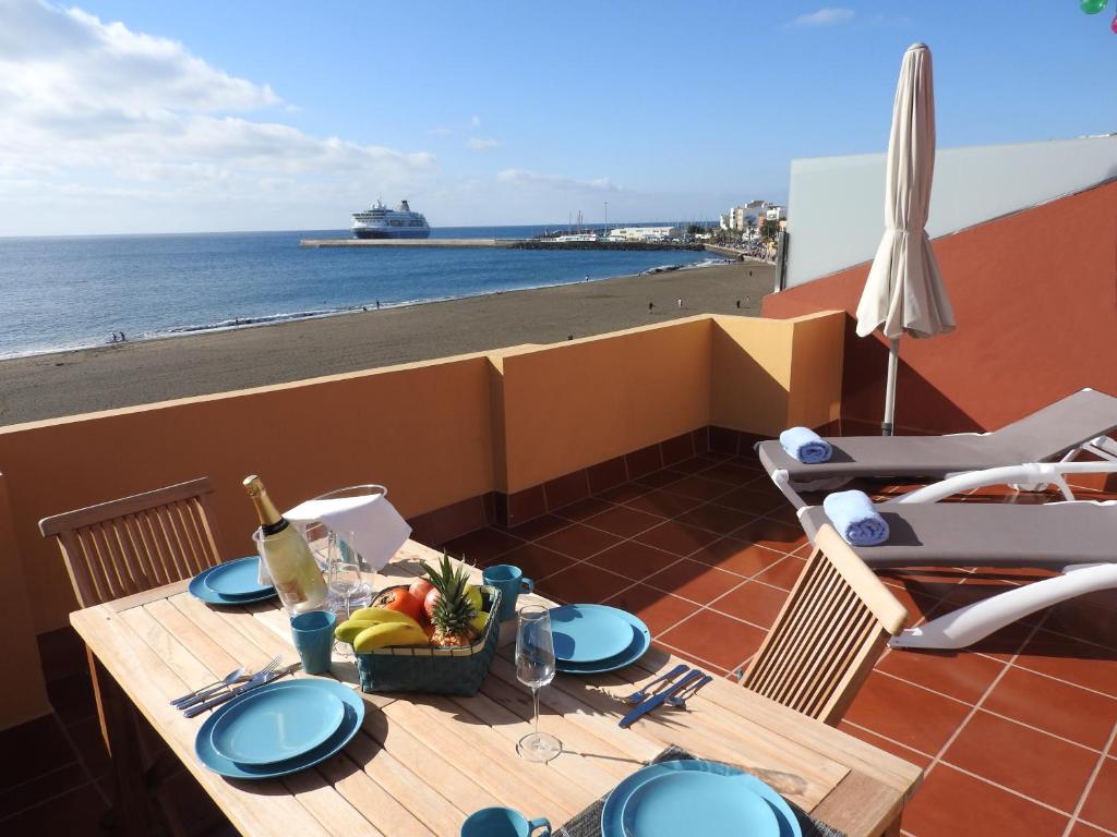 a table on a balcony with a view of the beach at Ocean View Penthouse II in Gran Tarajal