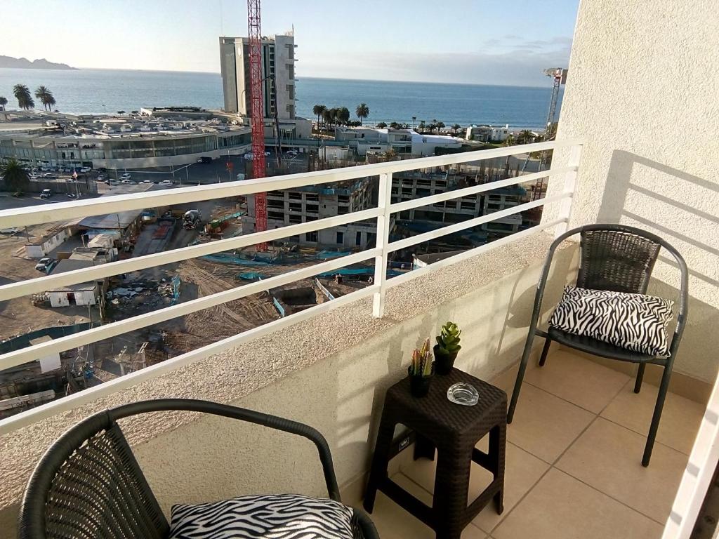 einen Balkon mit 2 Stühlen, einem Tisch und Meerblick in der Unterkunft Peñuelas excelente vista y ubicacion in Coquimbo