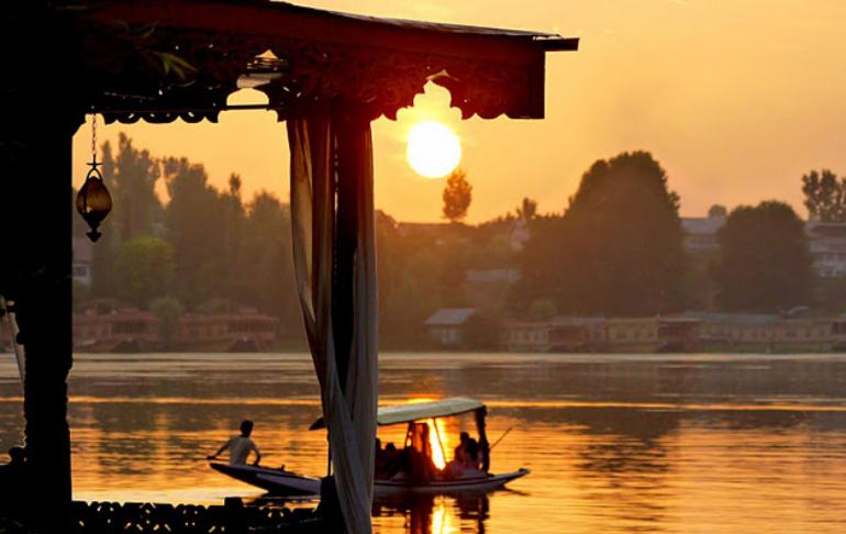 eine Gruppe von Menschen in einem Boot auf dem Wasser bei Sonnenuntergang in der Unterkunft Houseboat Lily of Nageen in Srinagar