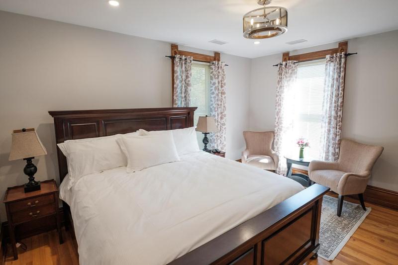 The Victorian Luxury Suites في Westport: غرفة نوم بسرير ابيض كبير وكرسي